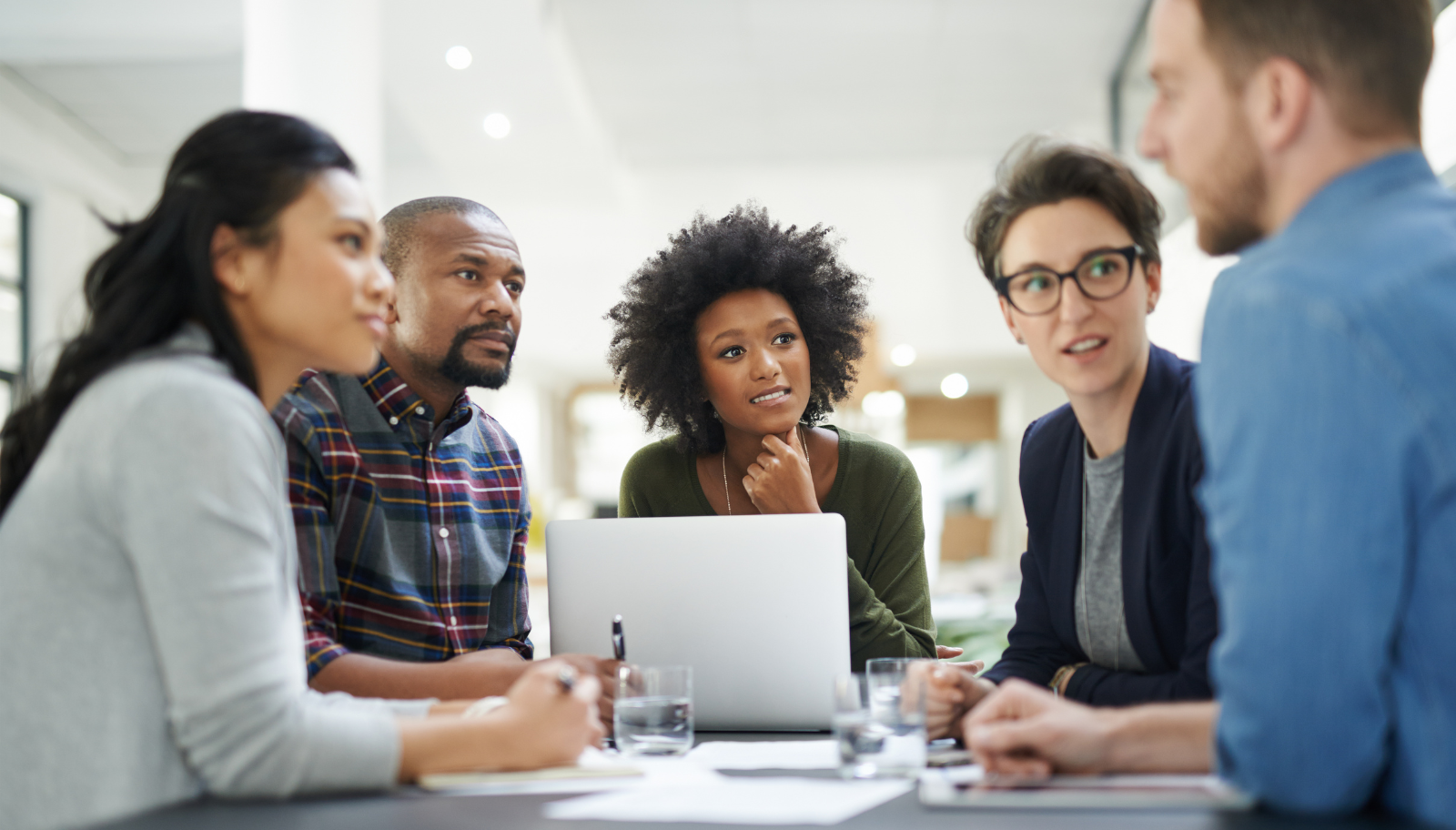 Sales team gathered around one laptop to review shared conference contacts